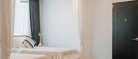 A bedroom with two beds, a black door, and a ceiling vent.