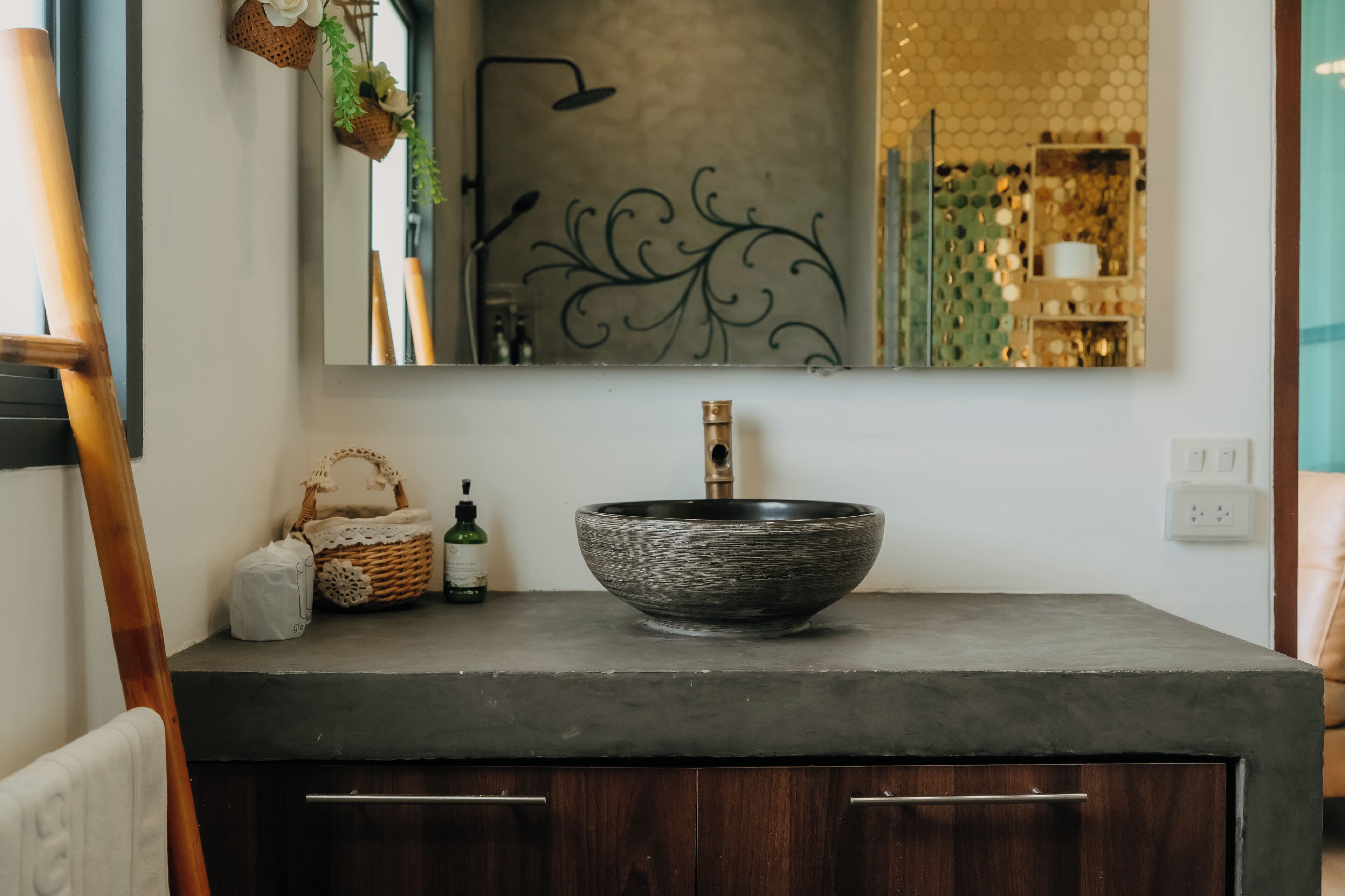 A bathroom with a large mirror, a vessel sink, wooden cabinets, and a decorative wall piece.