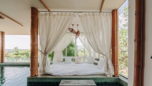 Habitación con cama en un rincón, vistas a zonas verdes y piscina.