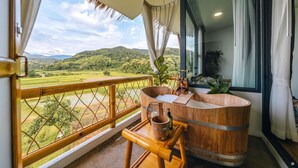 Una bañera de madera con vistas a un paisaje exuberante.