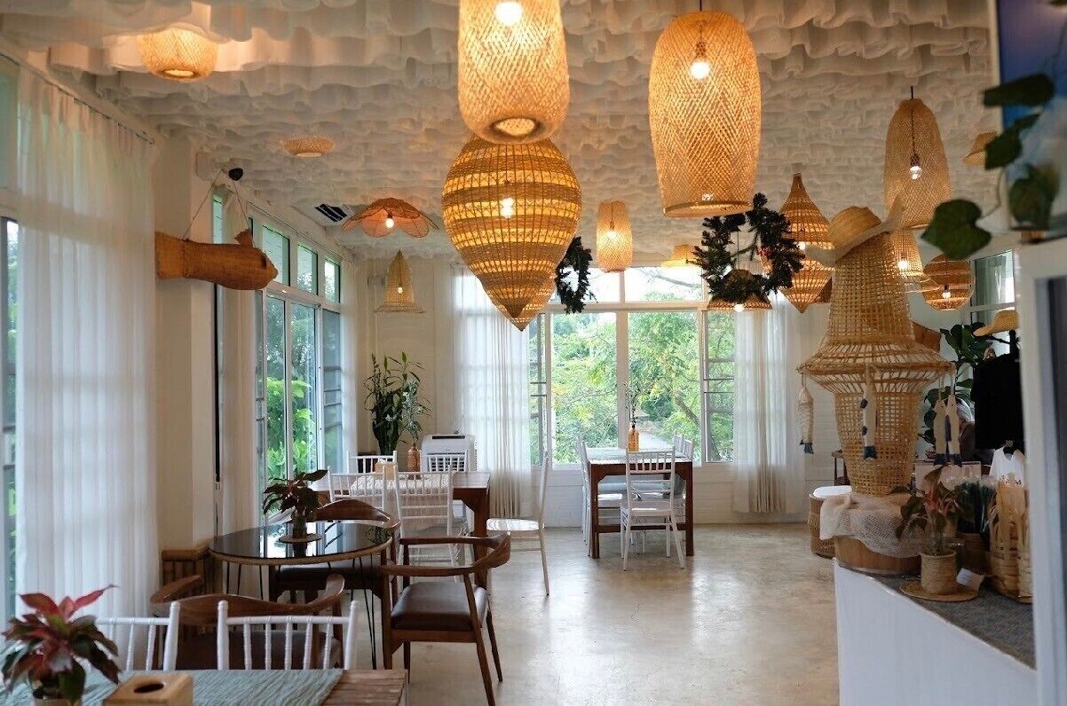 A spacious dining area with a round table and chairs, large windows, and hanging woven light fixtures.
