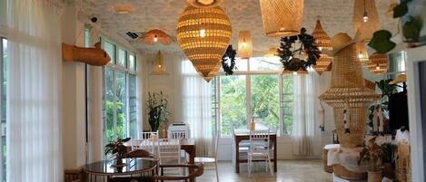 A spacious dining area with a round table and chairs, large windows, and hanging woven light fixtures.