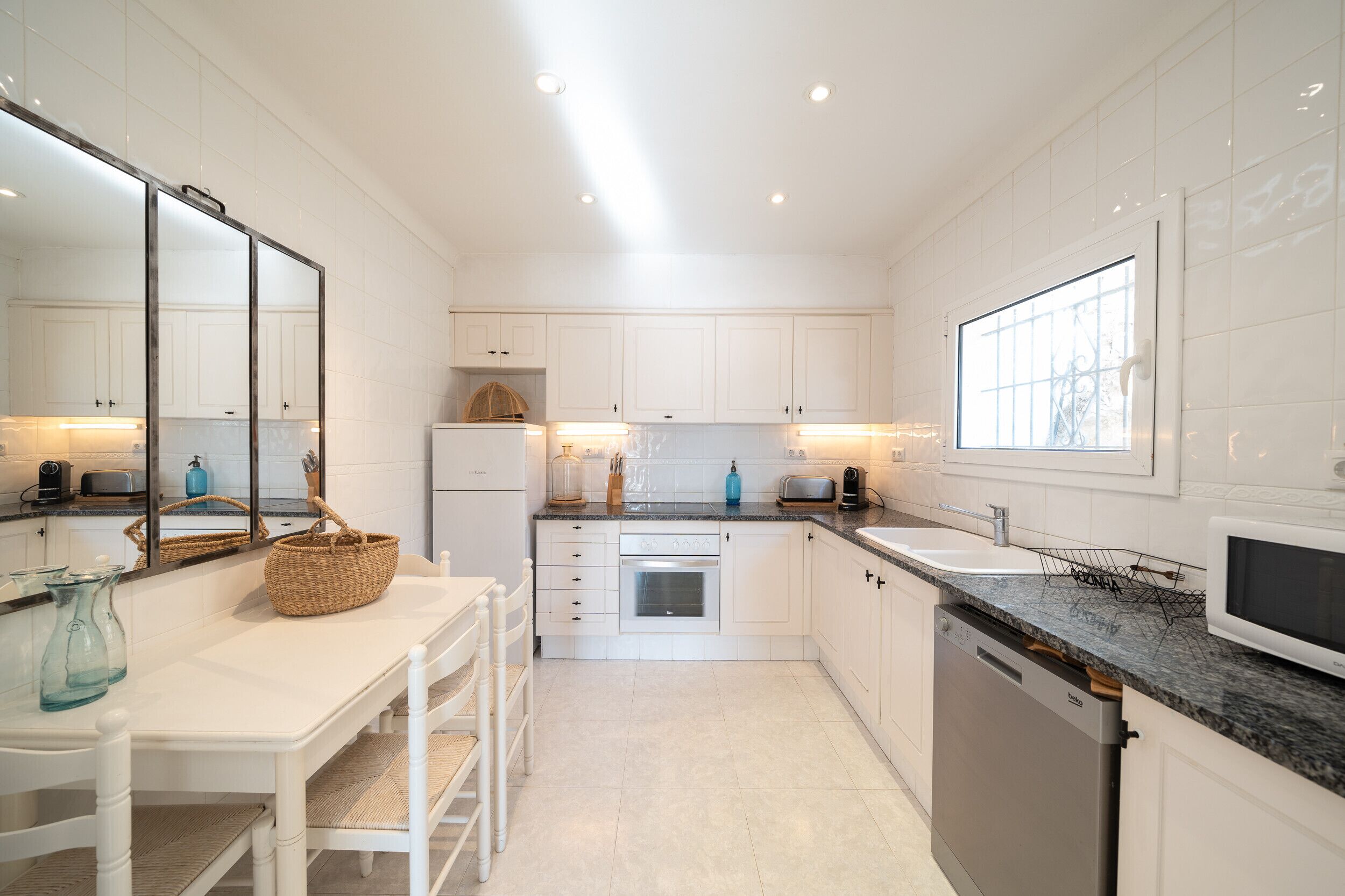 Una cocina moderna con armarios blancos, encimera de granito y electrodomésticos de acero inoxidable.