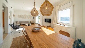 Un'area pranzo moderna con tavolo in legno, sedie in vimini e lampadari pendenti in vimini.