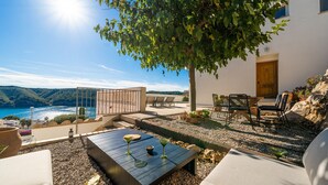 Una terrazza con tavolo e sedie di legno, vista mare.