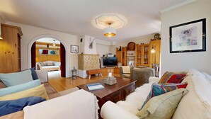 A cozy living room with a wooden floor, a television, and a bookshelf.
