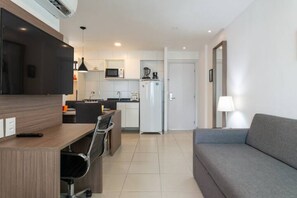 A modern kitchen with a dining area, a sofa, and a TV.