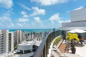 A rooftop terrace with a view of the city skyline and the ocean.