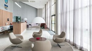Un hall d’hôtel moderne avec un comptoir d’accueil, un espace salon et de grandes fenêtres.