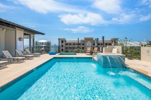 Une piscine dotée de chaises longues, d’un toboggan et offrant une vue sur un immeuble à multiples balcons.