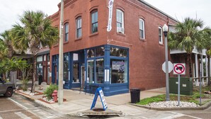 A red brick building with a blue corner, a sign for the Visitor Center, and a no parking sign. - In the heart of downtown Apalach w/ restaurants, shops & waterfront within steps (Apalachicola)