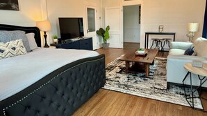 A modern hotel room with a large bed, a flat-screen TV, a dining area, and a living space. - In the heart of downtown Apalach w/ restaurants, shops & waterfront within steps (Apalachicola)