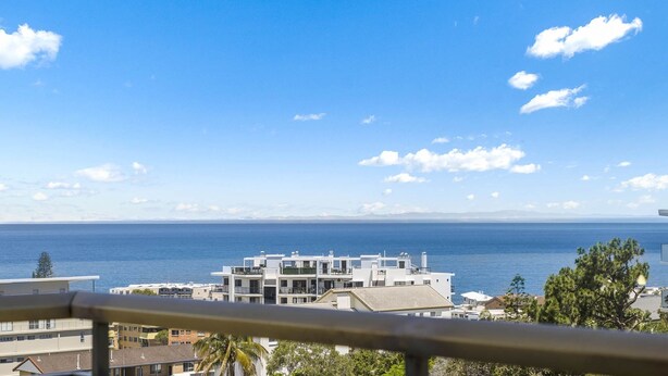 Une vue sur la côte, avec des bâtiments modernes, un ciel dégagé et la mer en arrière-plan.
