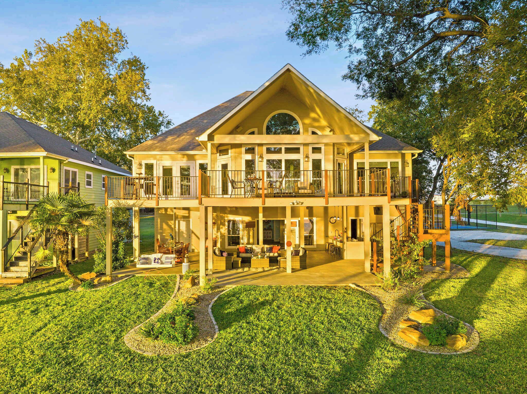 A two-story house with a balcony, a covered patio, and a well-maintained lawn.