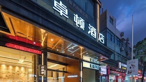 A hotel with a modern facade, large glass windows, and illuminated signage. - Dron Hotel (Dongguan)