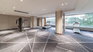 A modern gym with exercise equipment, a treadmill, and a patterned floor. - Dron Hotel (Dongguan)