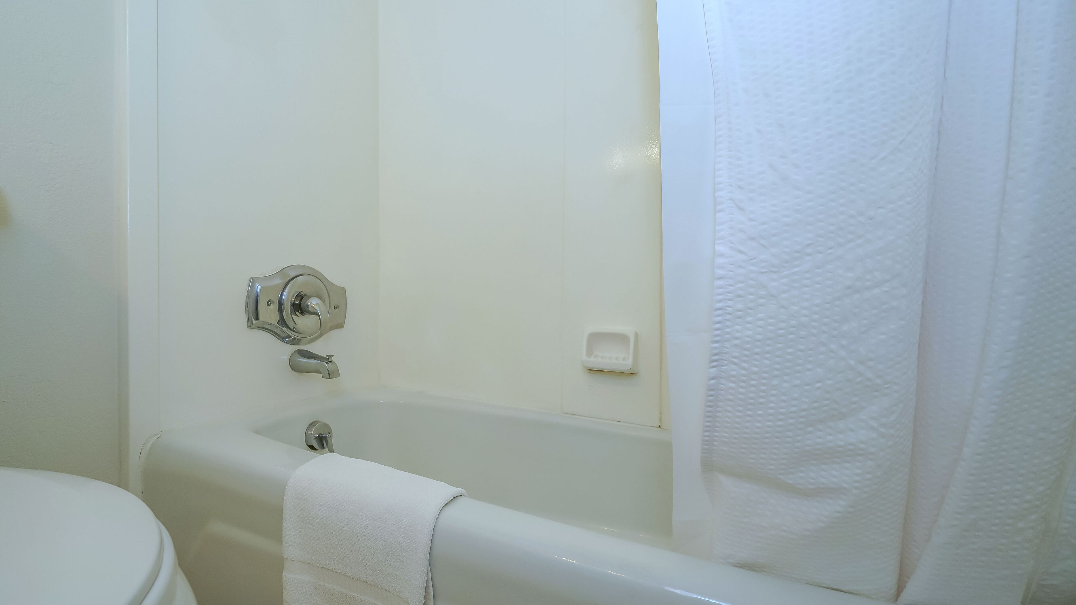 Ein Badezimmer mit einer weißen Wanne, einer Toilette und einem Handtuch, das am Wannenrand hängt.