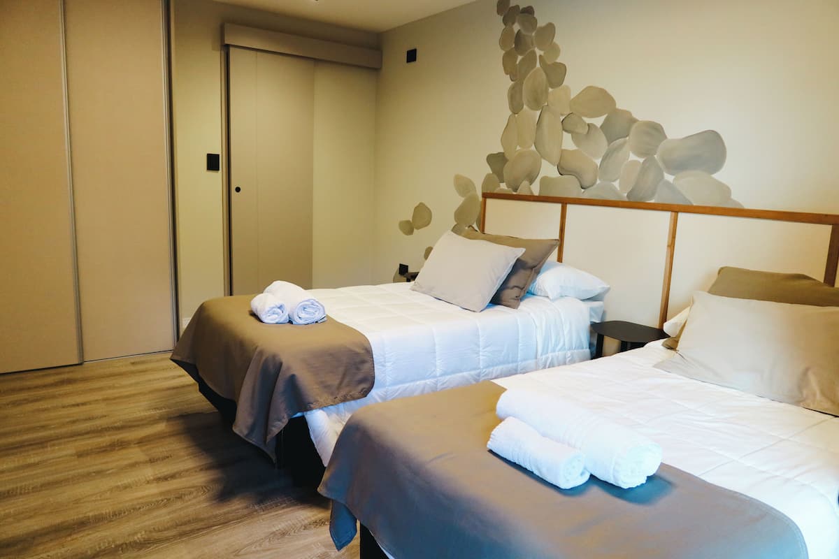 A hotel room with two beds, each with neatly folded towels.