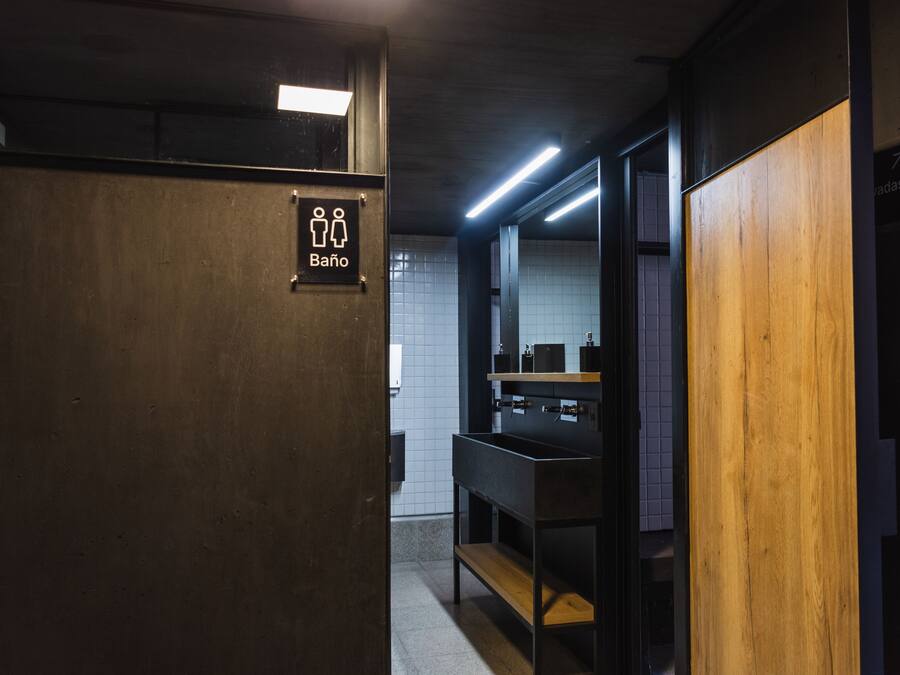 A public restroom with a sign indicating a men's bathroom, a sink, and a mirror.