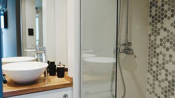 Une salle de bain moderne avec une douche à parois de verre, un lavabo blanc et un meuble-lavabo en bois.