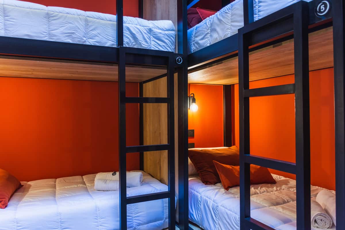 A bunk bed room with orange walls and a wooden floor.
