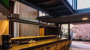 A bar area with a coffee machine, stacked plates, and glasses on a shelf. - FAZ HOSTEL BOUTIQUE (Córdoba)