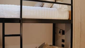 A bunk bed with a ladder, a bedside table, and a wall-mounted light fixture.