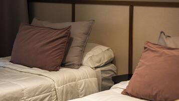 A hotel room with two beds, a headboard with a leaf design, and a towel on the floor.