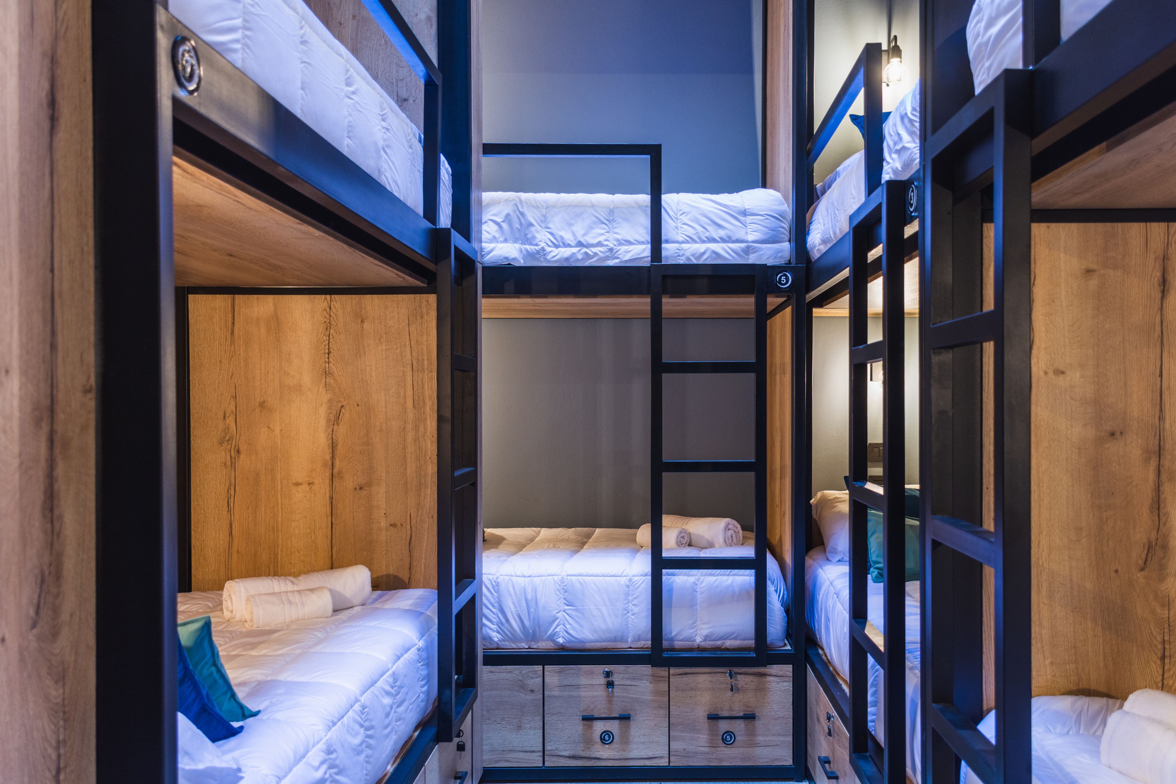 Habitación con literas, paredes de madera y una escalera.