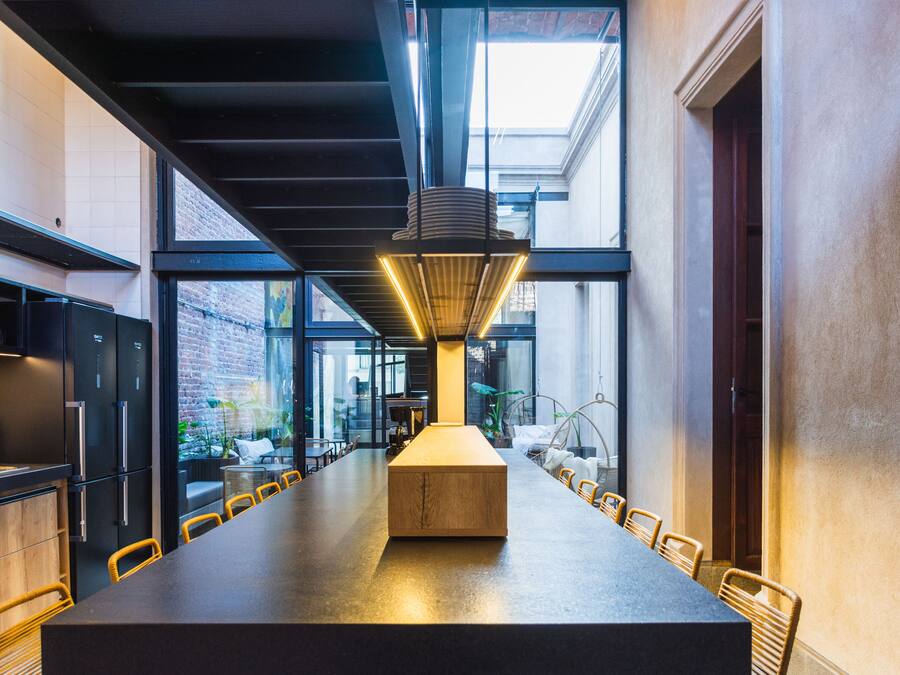 A modern kitchen with a long dining table, black cabinets, and a unique hanging light fixture.