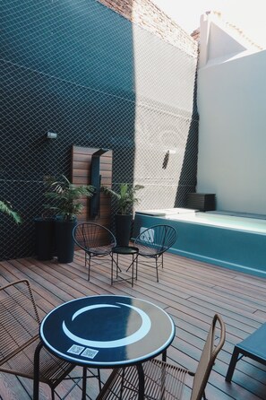 Un espace extérieur aménagé avec une table ronde, deux chaises et des plantes en pot.
