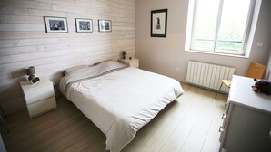A bedroom with a bed, bedside tables, a radiator, a window, and framed pictures on the wall. - Cottage on private grounds (Perrou)