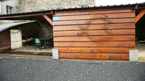 A wooden building with a metal sculpture of a face on the side. - Cottage on private grounds (Perrou)