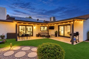 A residential property with a covered patio, outdoor seating area, and a well-maintained lawn.