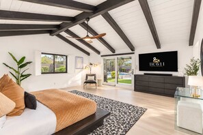 A modern bedroom with a large bed, a television, and a view of the outdoors.