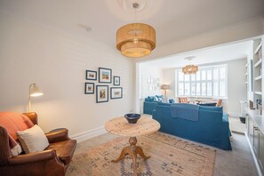 A living room with a sofa, a coffee table, a lamp, and framed pictures on the wall. - 21 Park Lane, Aldeburgh (Suffolk)