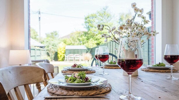 Una mesa de madera con platos de comida y copas de vino.