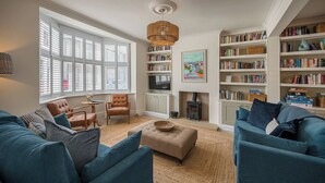 Una sala de estar con sofá, sillones, televisor, estantería y chimenea.