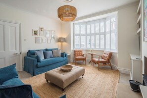 A living room with a blue sofa, a beige ottoman, and two leather armchairs.