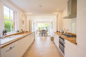 A modern kitchen with a central island, wooden countertops, and a dining area with a table and chairs.