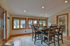 A dining area with a wooden table and chairs, large windows, and a view of the backyard. - Bent Creek Chalet, Sauna,Jacuzzi,Fire pit and OD shower (Asheville)