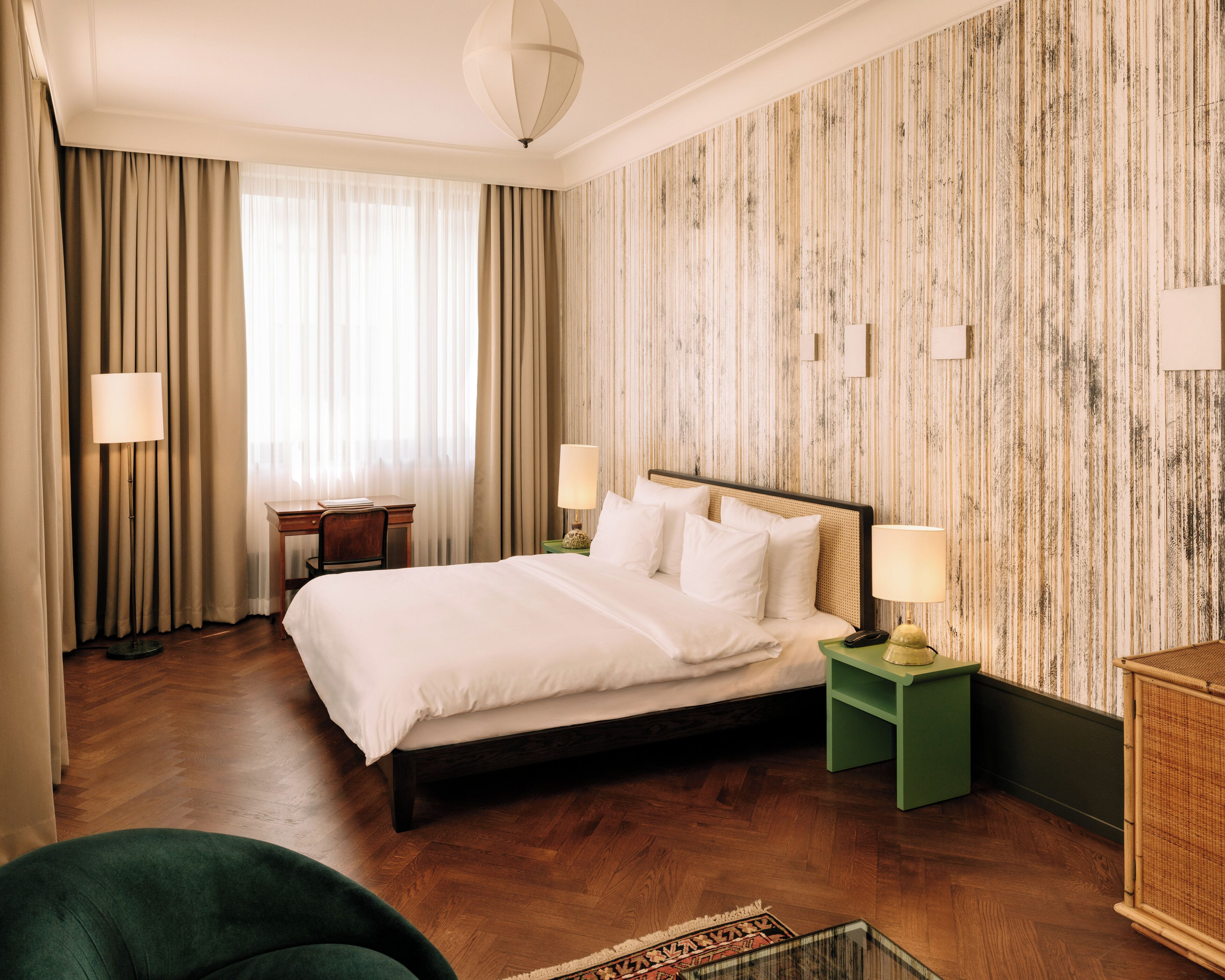 A hotel room with a large bed, two bedside tables with lamps, a desk, and a chair.