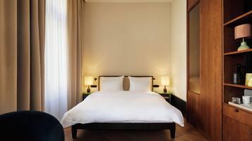 A hotel room with a large bed, two bedside lamps, a wooden wardrobe, and a chair.