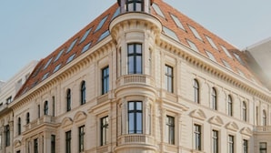 A corner of a building with a distinctive red-tiled roof and a rounded corner with a balcony. - Château Royal Berlin (Berlin)