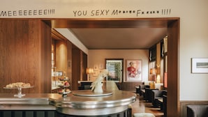 A bar area with a wooden backdrop, a dessert display, and a bar counter with stools. - Château Royal Berlin (Berlin)