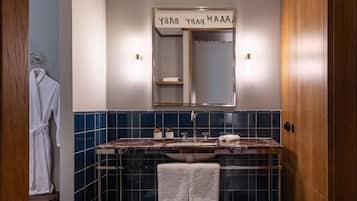 Un baño con tocador, espejo y toallero.