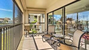 A balcony with a view of the city, furnished with chairs and a table, and a lamp. - NEW NEW   Burnt Store Marina Front,  Premier Corner Unit, 30-Day Minimum Retreat (Punta Gorda)
