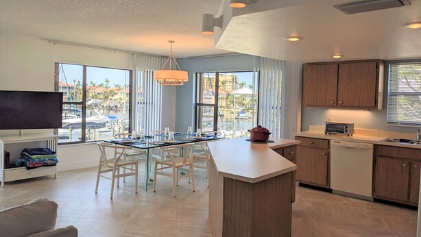 A modern kitchen with a central island, white cabinetry, and a view of the marina. - NEW NEW   Burnt Store Marina Front,  Premier Corner Unit, 30-Day Minimum Retreat (Punta Gorda)