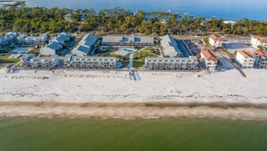 Eine Luftaufnahme eines Küstenhotels mit mehreren Gebäuden, einem Strand und einem Schwimmbad.
