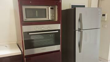 A kitchen with a built-in microwave, oven, and refrigerator.